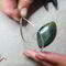 Handcrafting the Gary Green Jasper pendant, with sterling silver wire being carefully wrapped around the stone during the creation process.